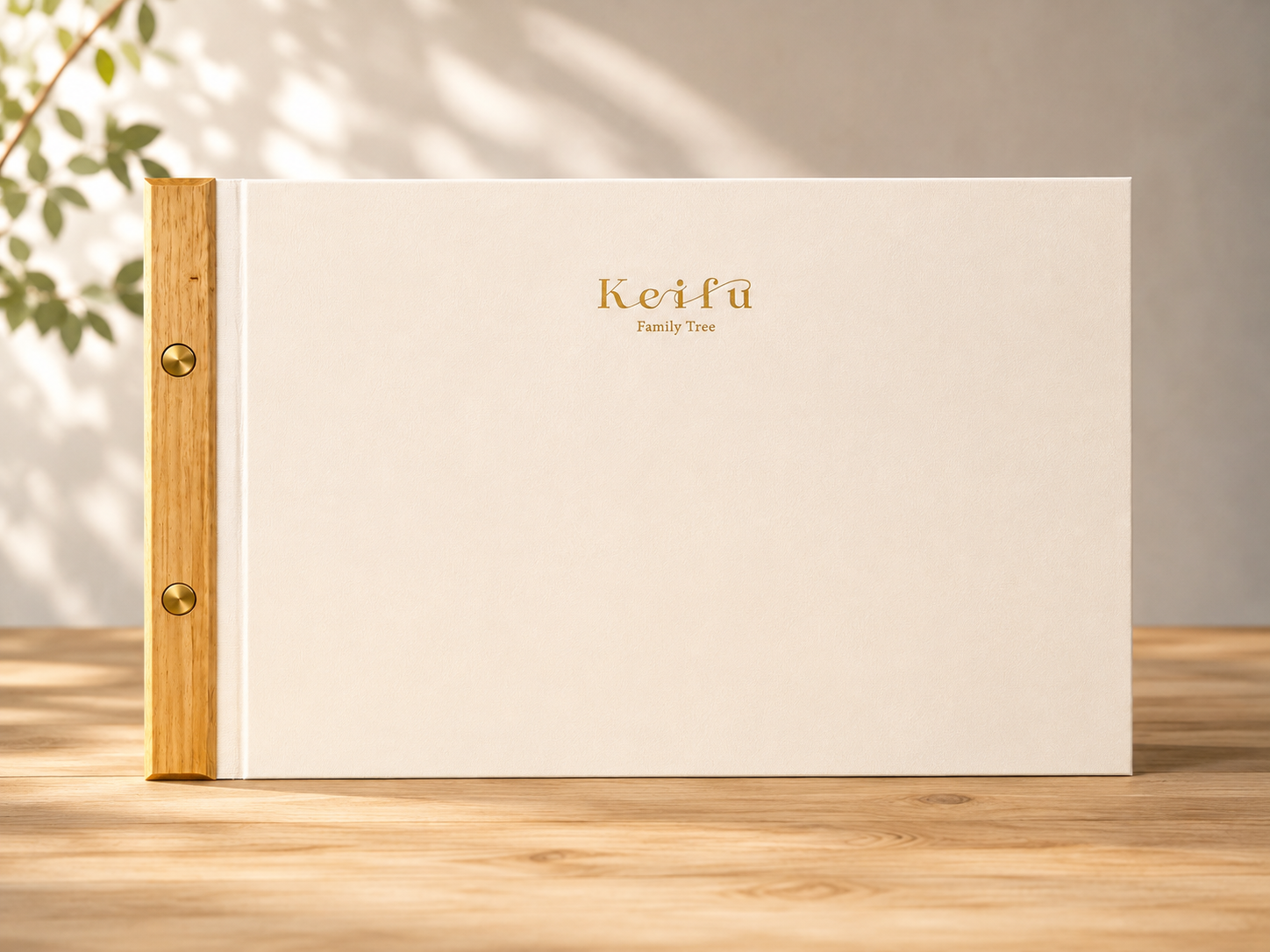 家系図冊子「Keifu Book」の表紙。生成りの表紙に金の箔押しロゴ、木の背に真鍮のビス